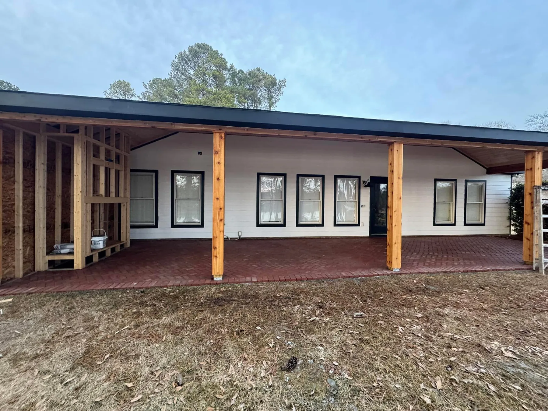 Home exterior with covered porch, white siding, dark trim and exposed wood posts