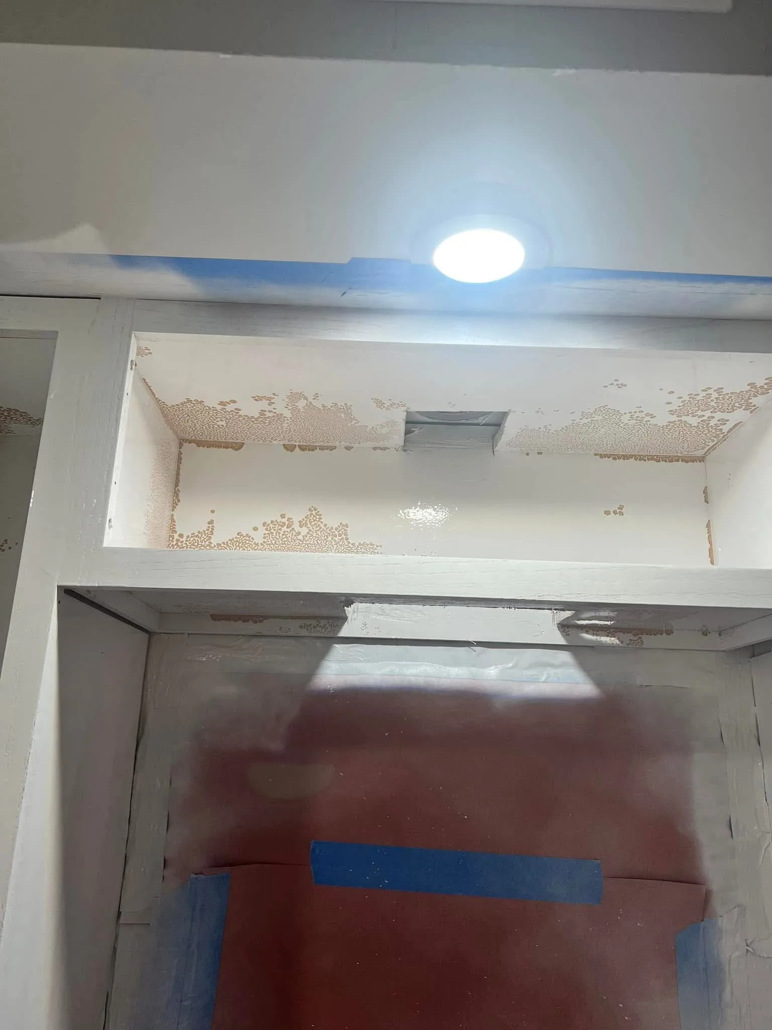 Close-up of cabinet and wall area with visible peeling, staining and prep work before drywall repair and repainting