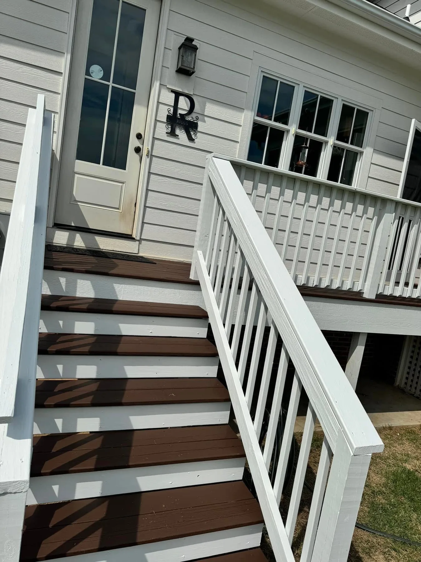 Porch stairs with brown treads and clean white railings after refinishing