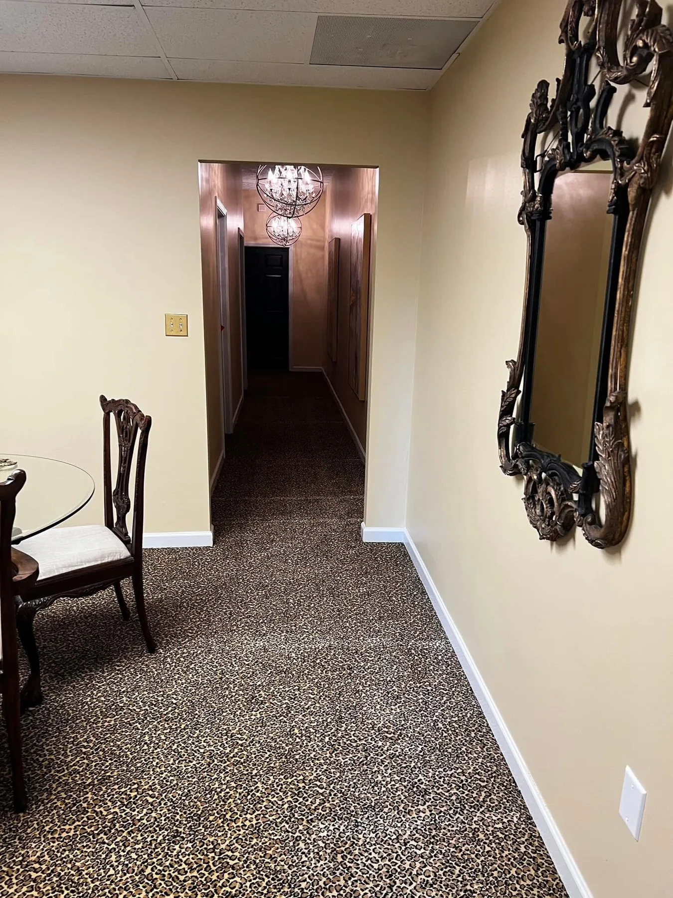 Interior hallway with light neutral walls, white baseboards and ornamental mirror